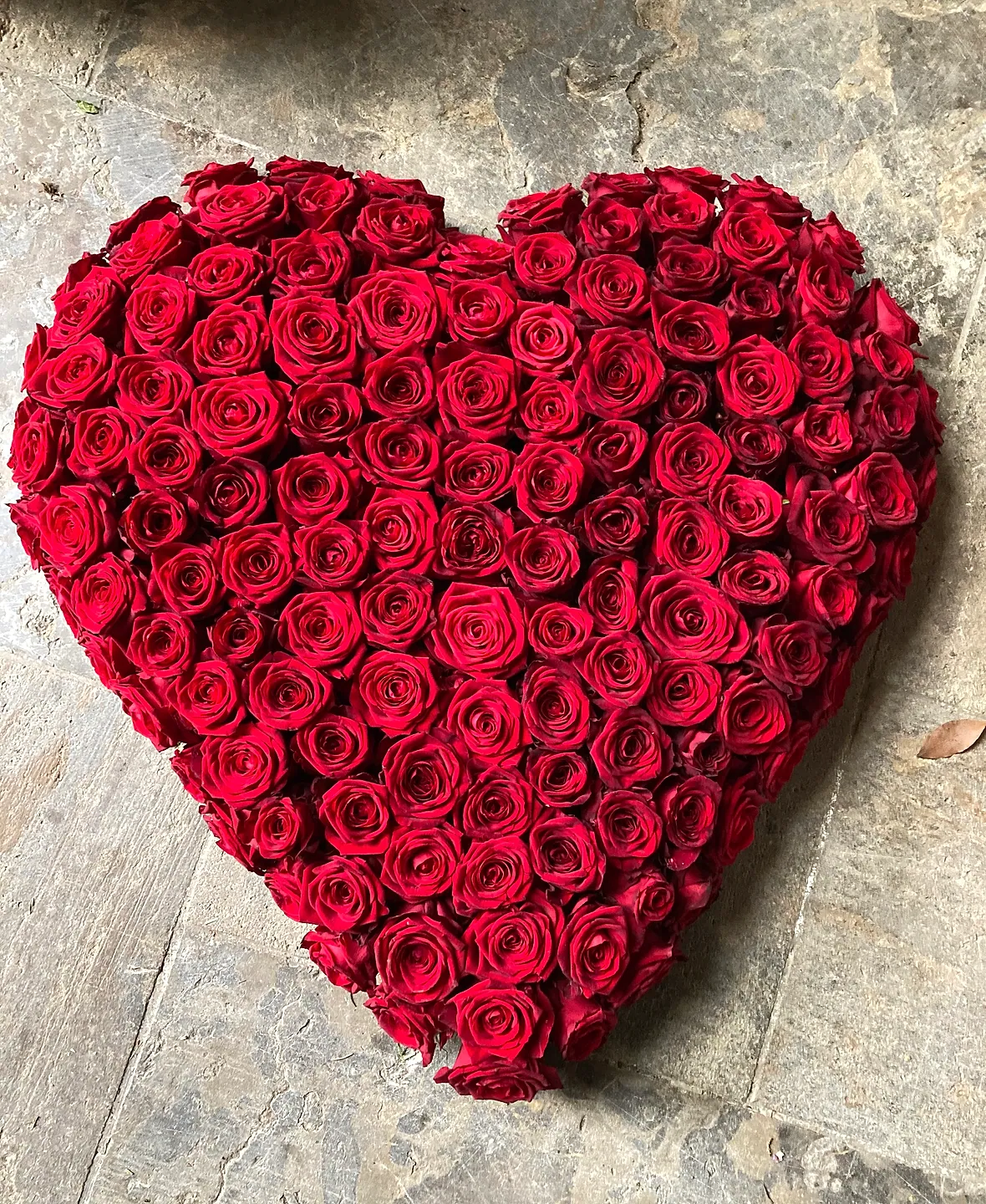 Herz aus roten Rosen, von Hand gelegt, auf einer Natursteinplatte